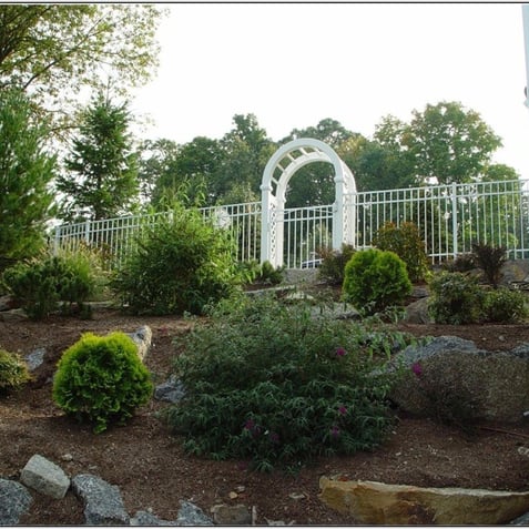 White arbor leading to or from a garden