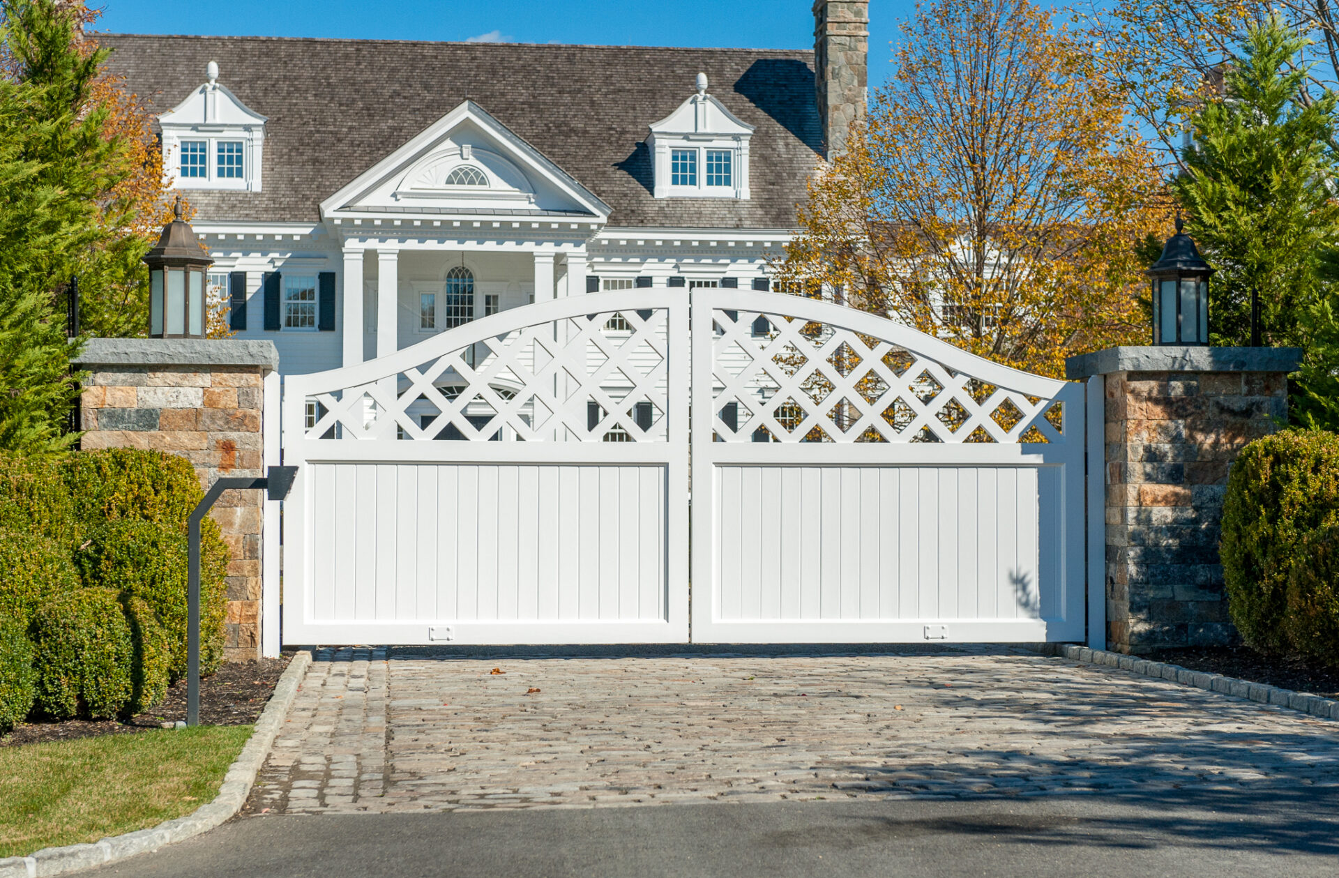 White composite driveway gate in front of a home