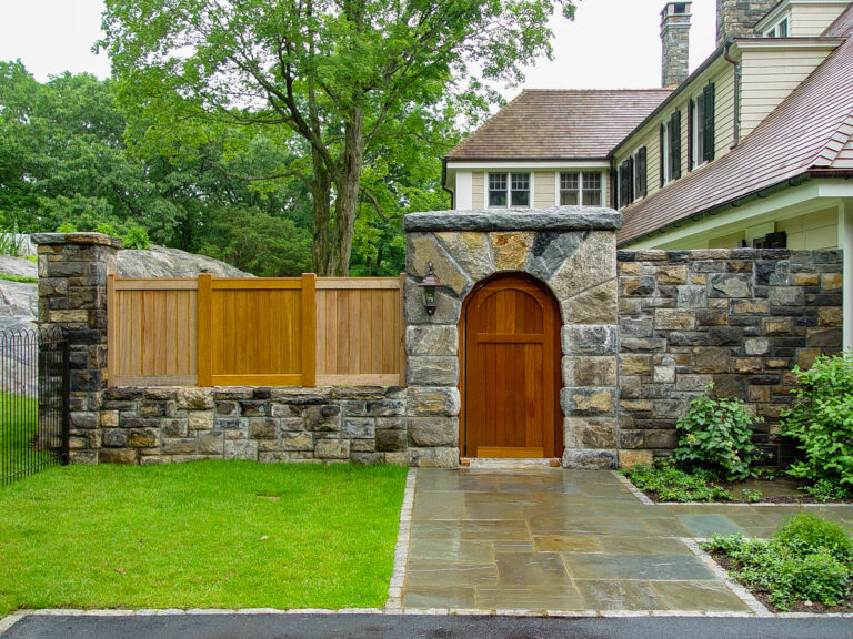 Stone custom fence with covered wooden gate and wood slats