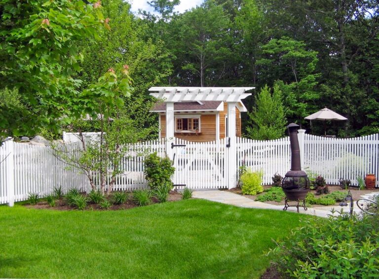 A scalloped white picket wood fence with an arbor.