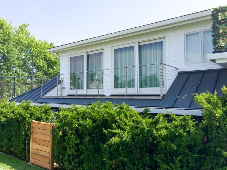 Cable railings form a French balcony outside the sliding full-size windows on the second story of a home.