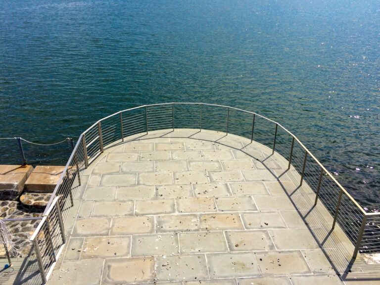 Cable railings extend out and semi-circularly around a flagstone platform that’s surrounded by water.