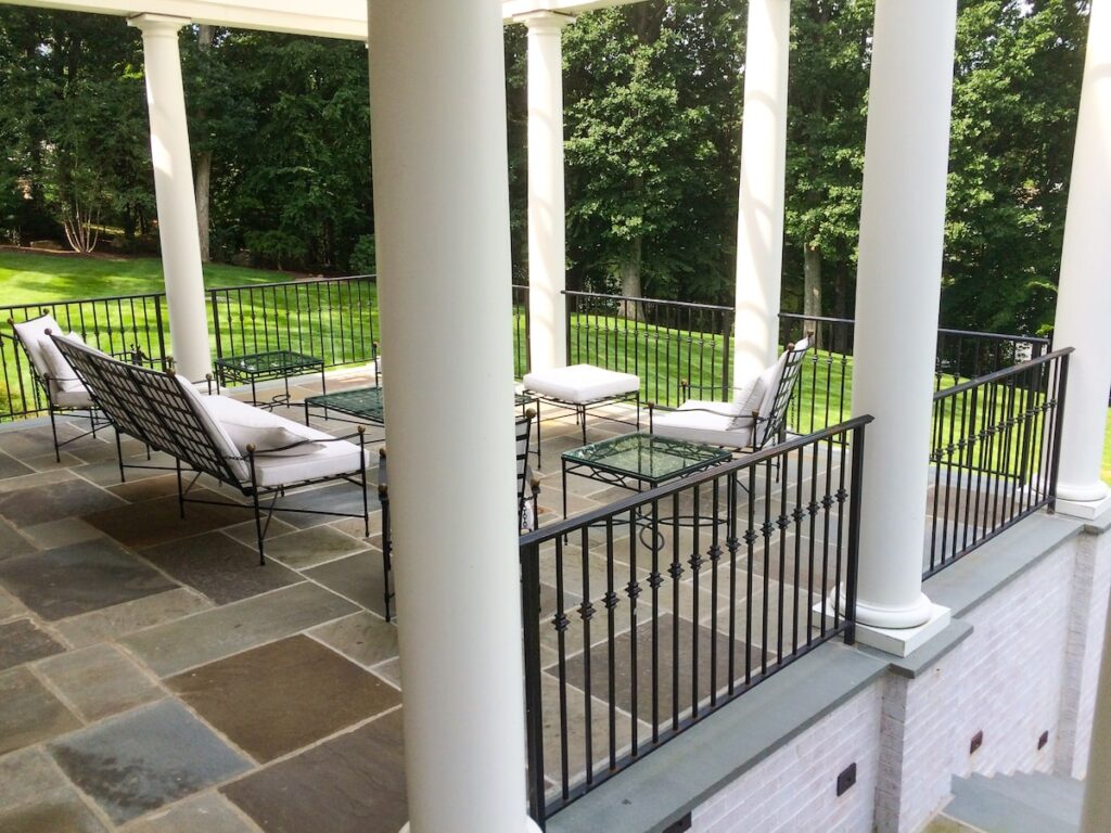 A spacious balcony with white columns and wrought iron railings.