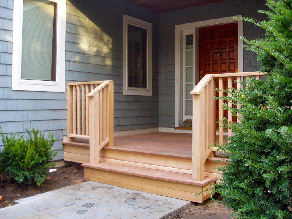 A natural wood porch railing frames the entryway of a home.