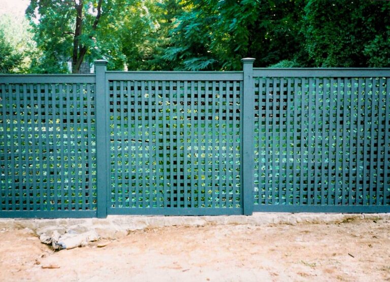 A dark green wood lattice fence used to keep out deer.