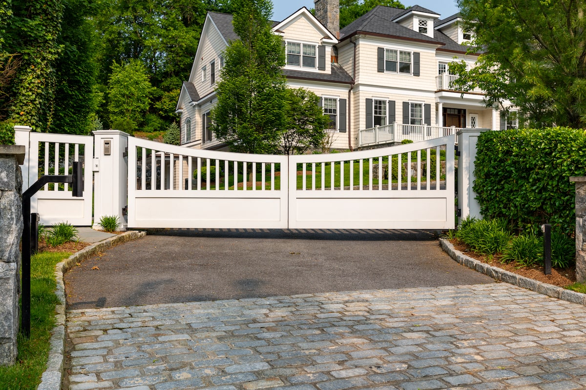 sleek white modern driveway gate with natural stone paving