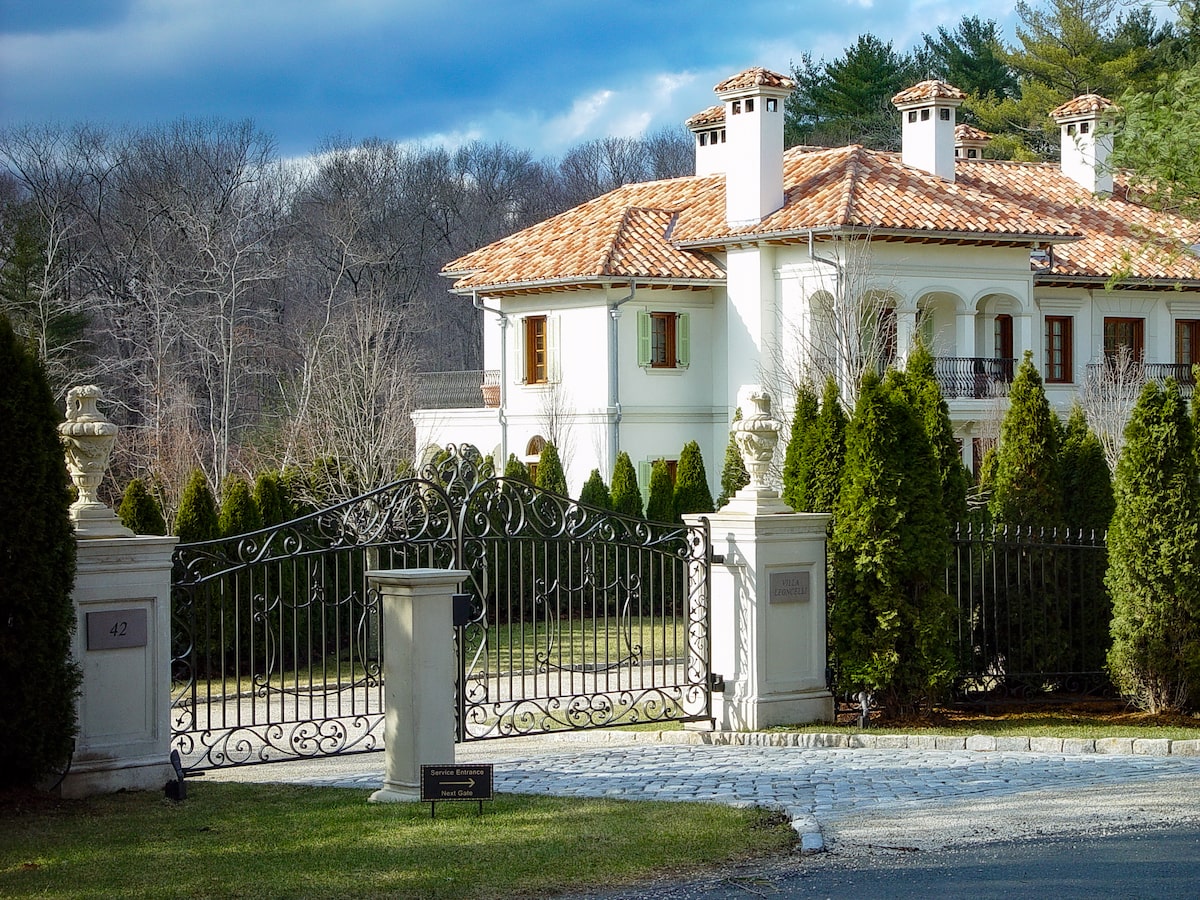 black swing metal driveway gate with pillars and urns