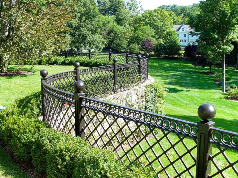 A wrought iron metal fence curves along this stone retaining wall.