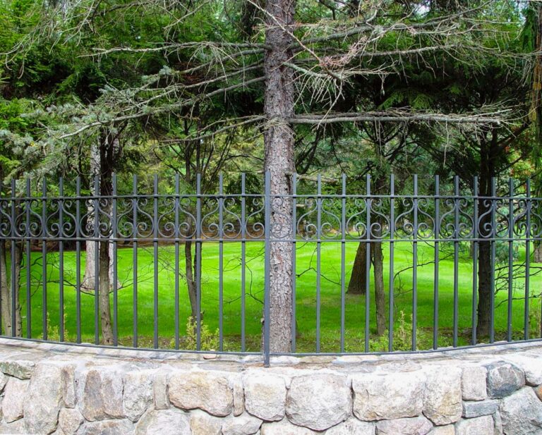 A wrought iron metal fence on a stone wall.