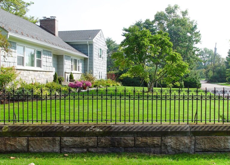 Classically designed wrought iron metal fencing on a stone wall.