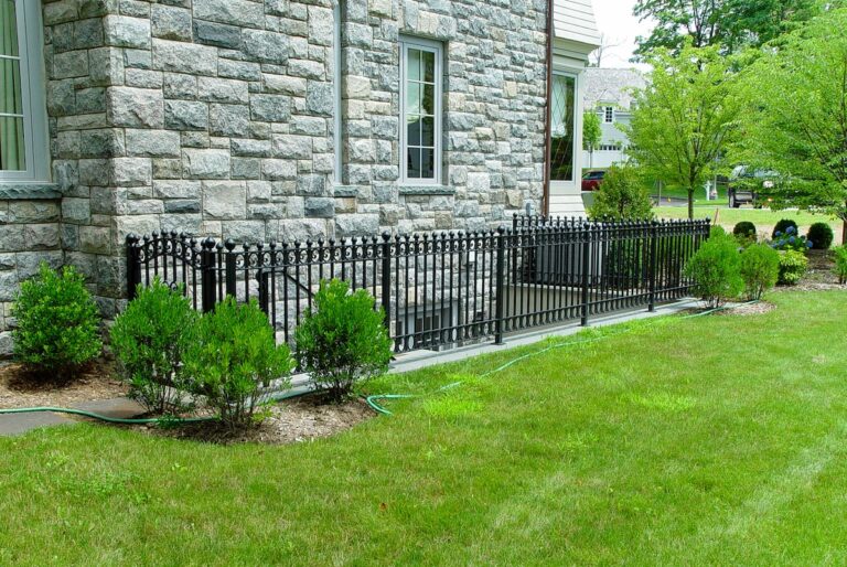 A wrought iron metal fence with an entryway around an outdoor staircase to the basement.