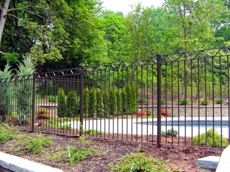 A tall black metal fence is topped with a wavy design in the same material.