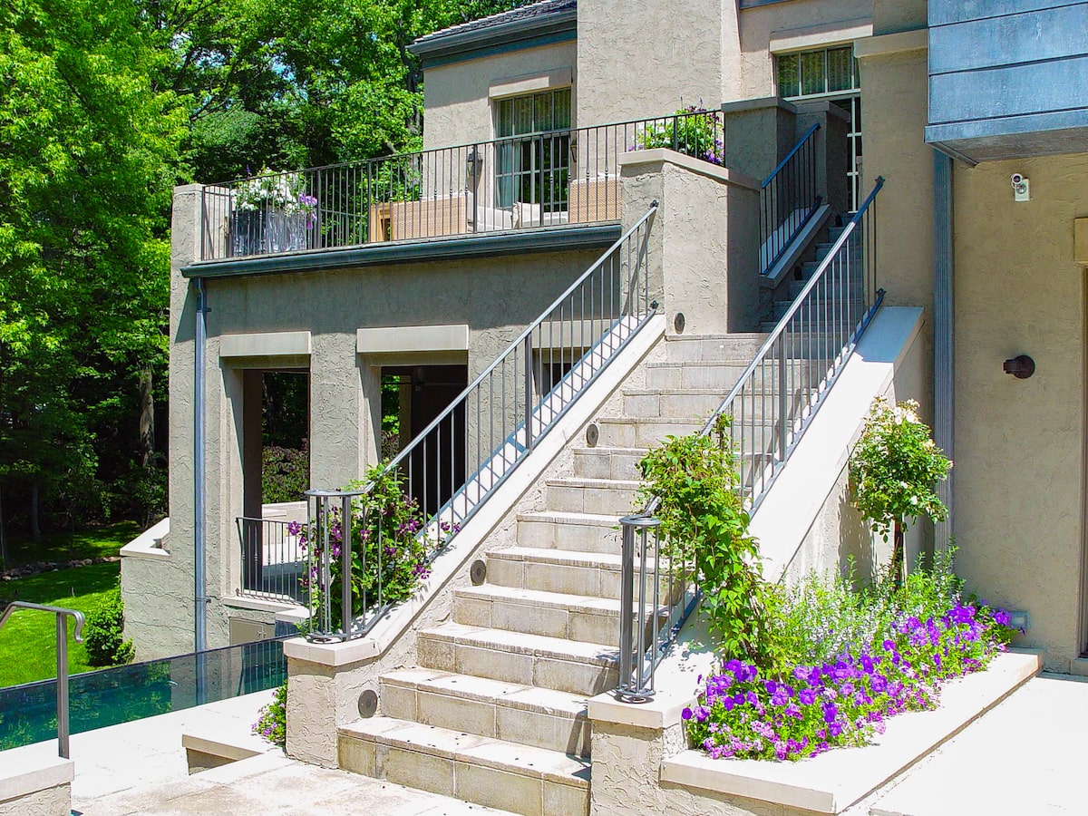 A silver-colored wrought iron outdoor metal stair railing matches the blue-ish gray and beige tones of this home’s exterior.
