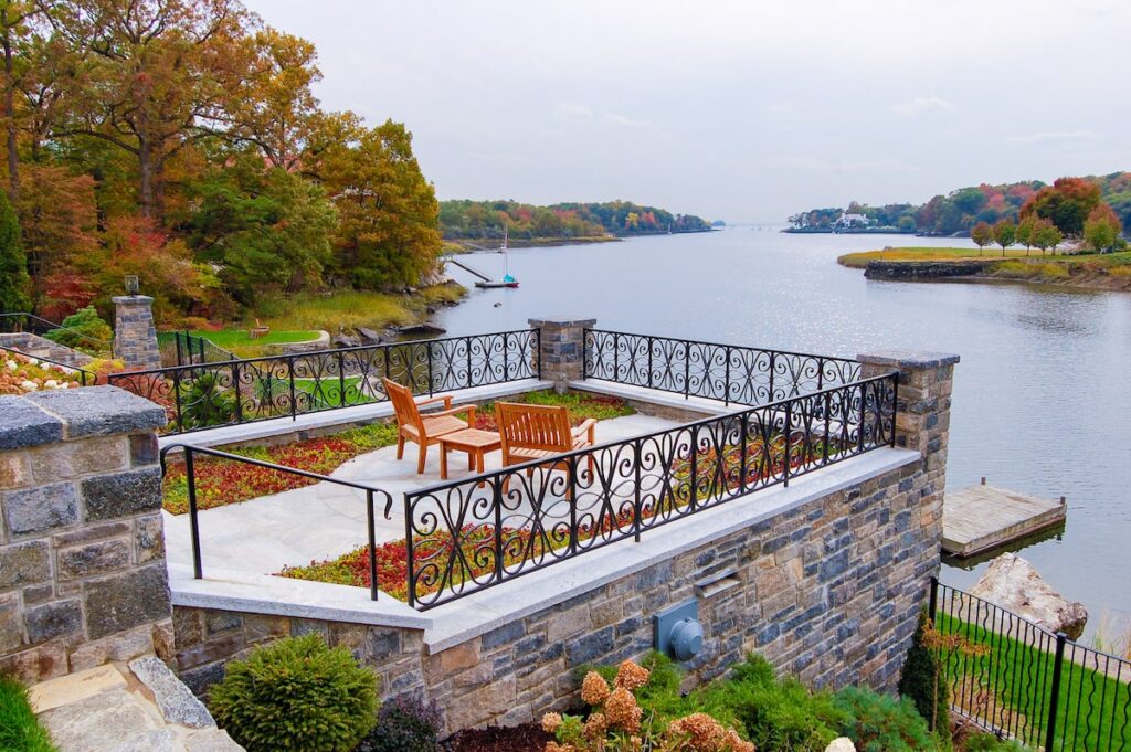 A black metal railing around a balcony overlooks a lake.