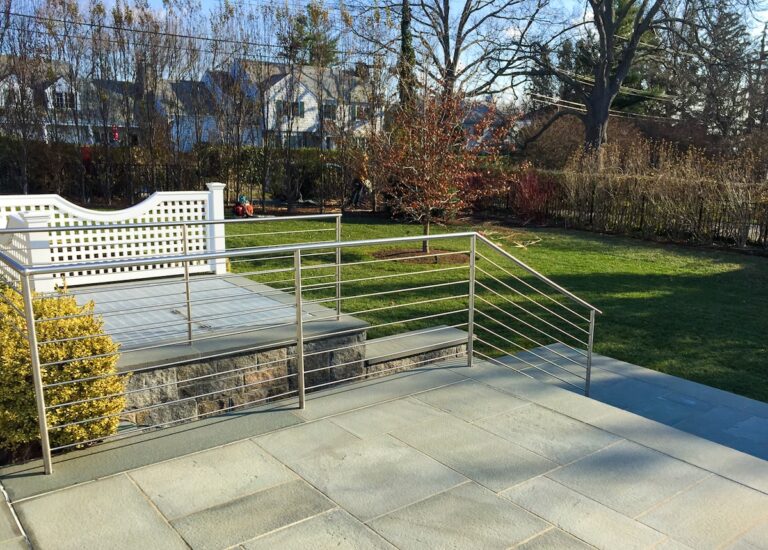 The cable railing that runs along the side of this deck extends down to form a railway for a short staircase leading to a lower level.