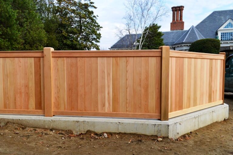 A wooden privacy fence sits on a concrete slab.
