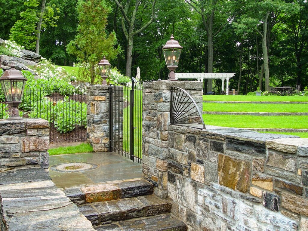 A stone walking with a wrought iron hooped gate and railings leads out to the lawn.