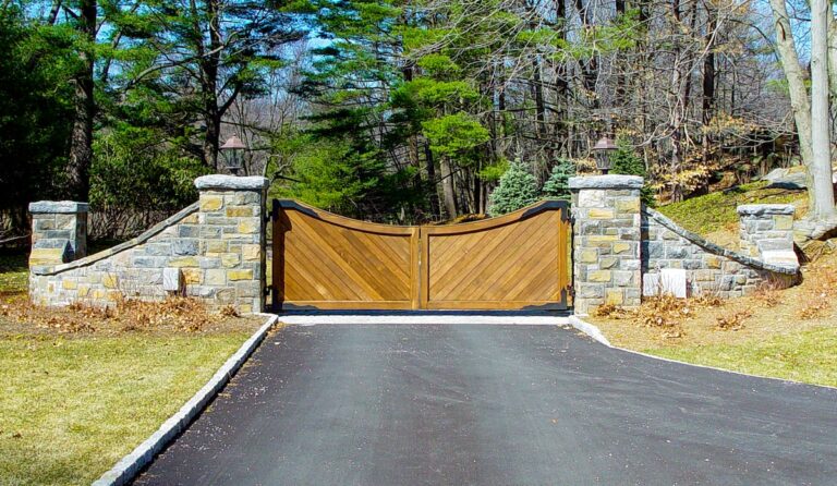 A solid wood gate with diagonal panels and strap hinges sits between stone walls.