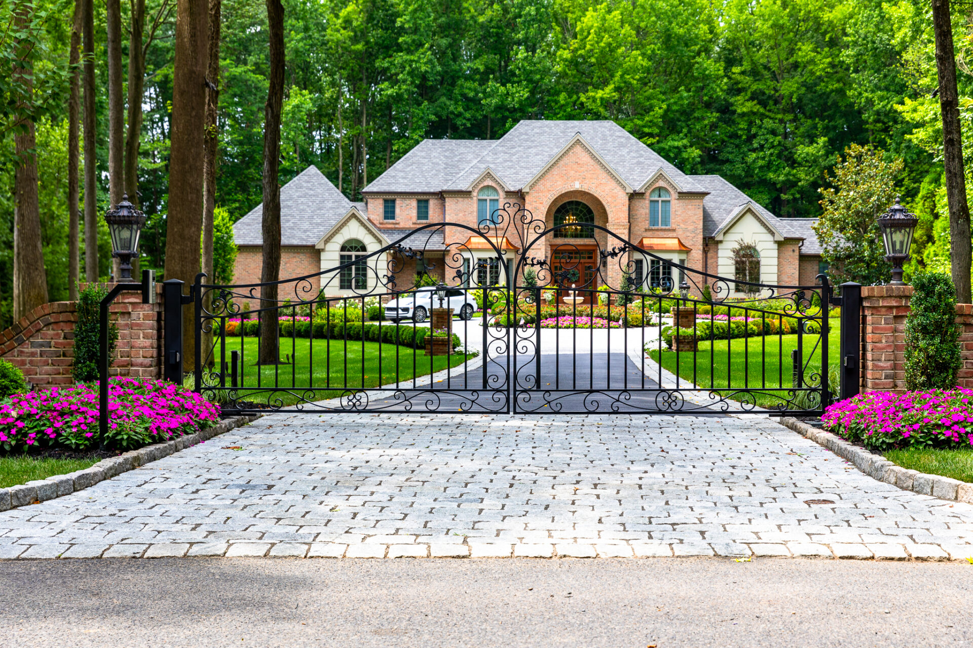 automatic driveway gate made from iron bordering a stunning property