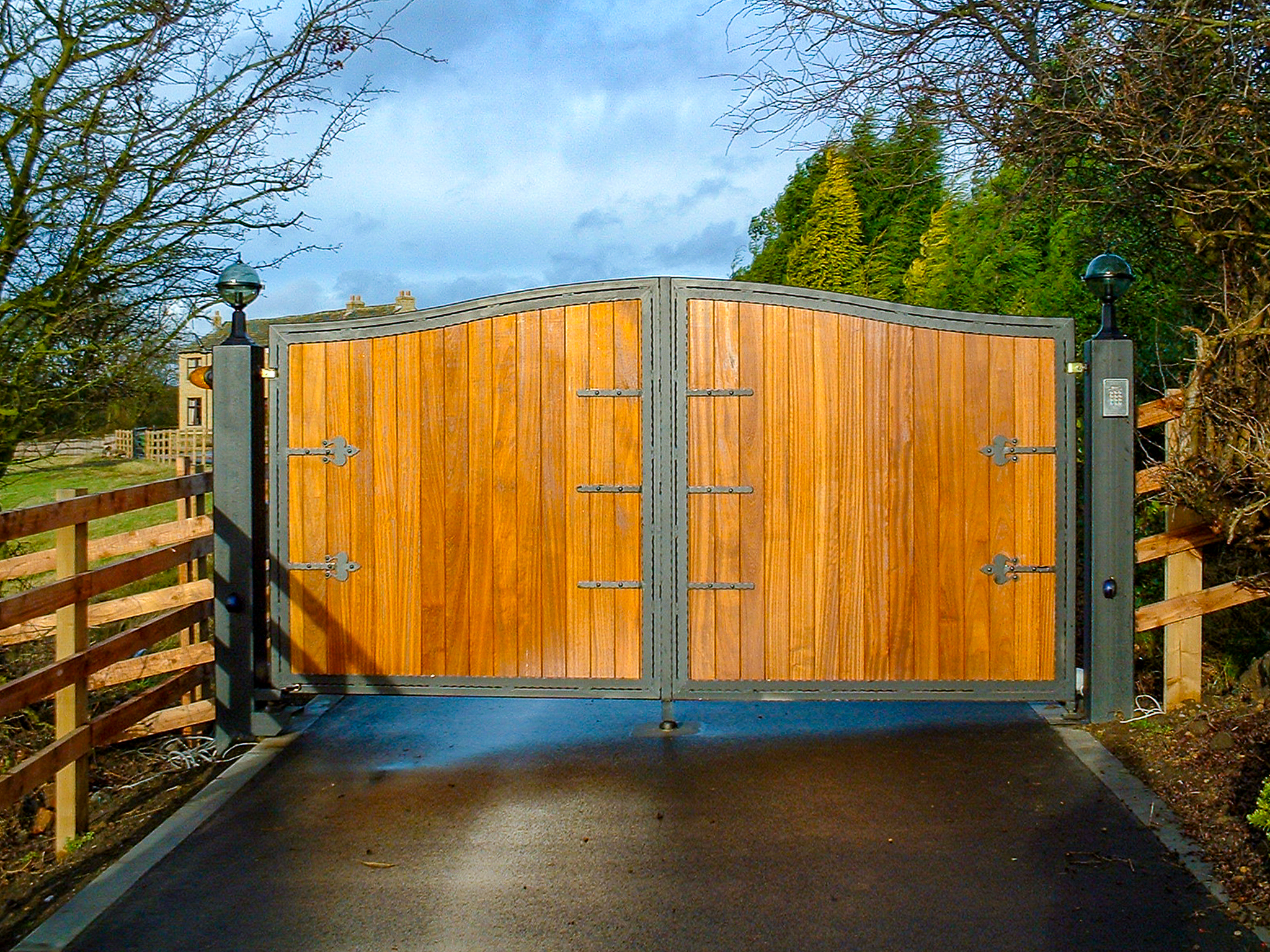 combined metal and wood driveway gate at farmhouse entryway