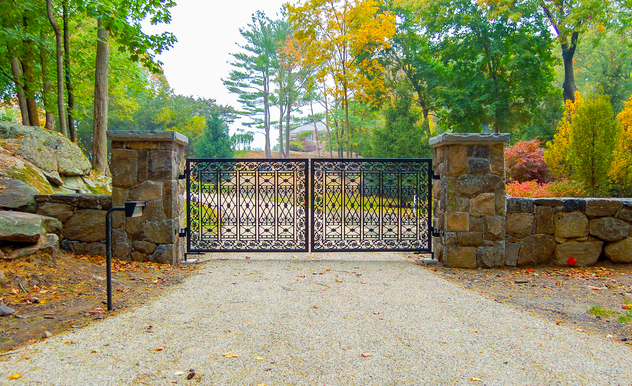 driveway gate designed from wrought iron and stonewall pillars