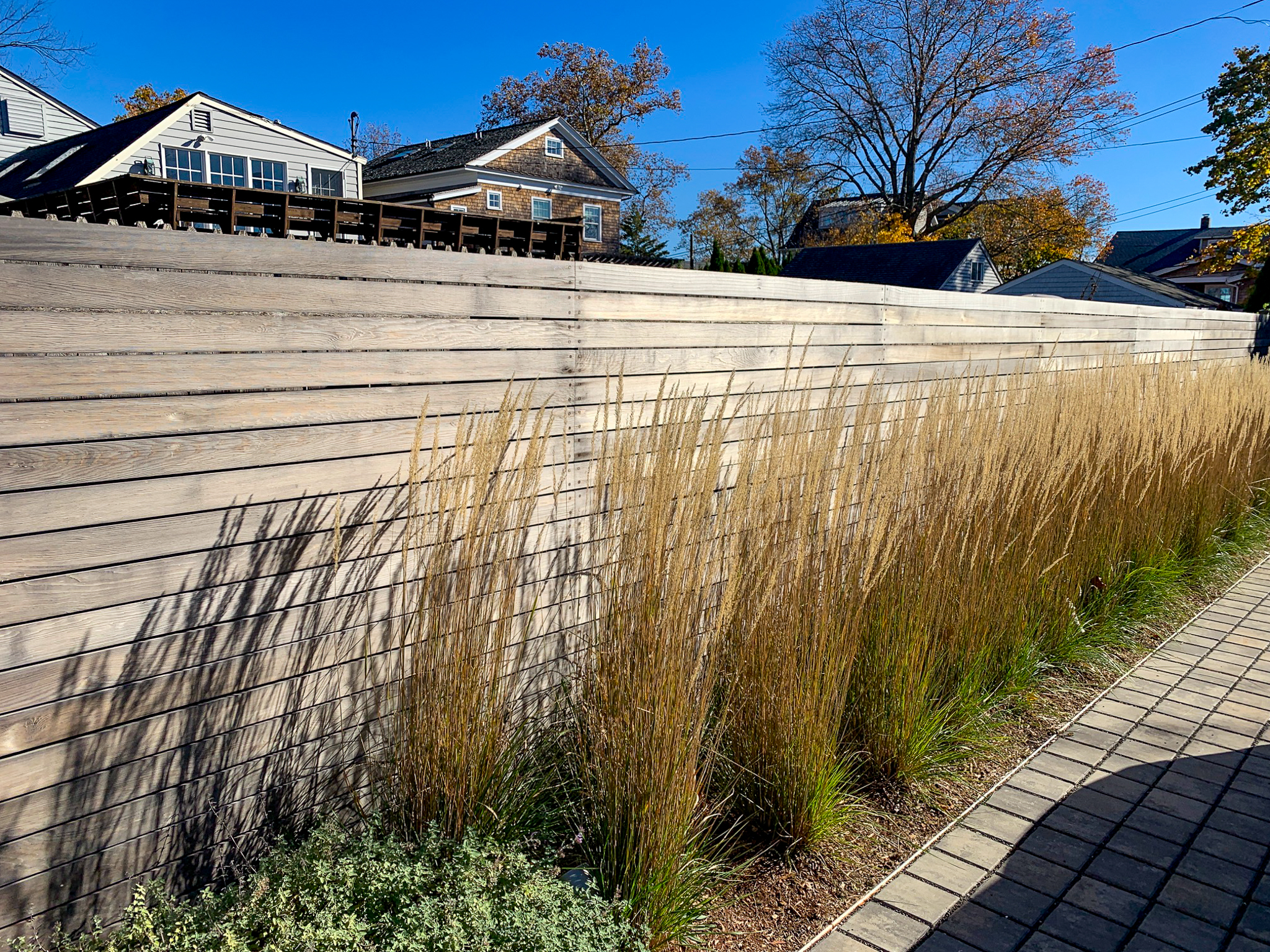 horizontal wood privacy fencing with tall grass in front