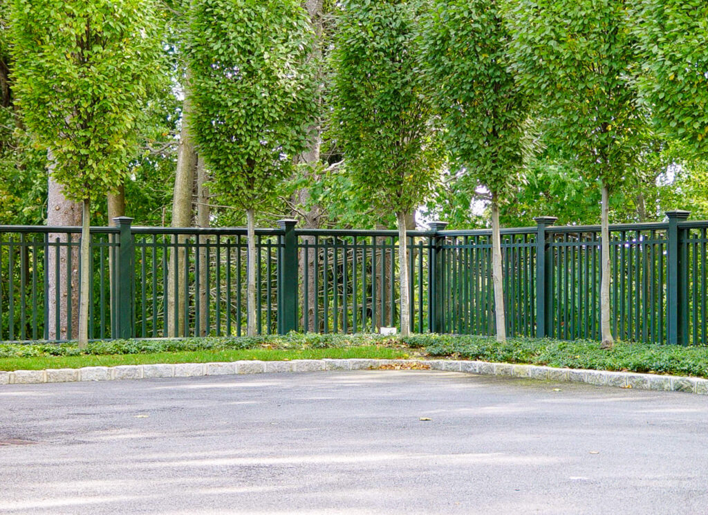 green fence bordering a small parking area