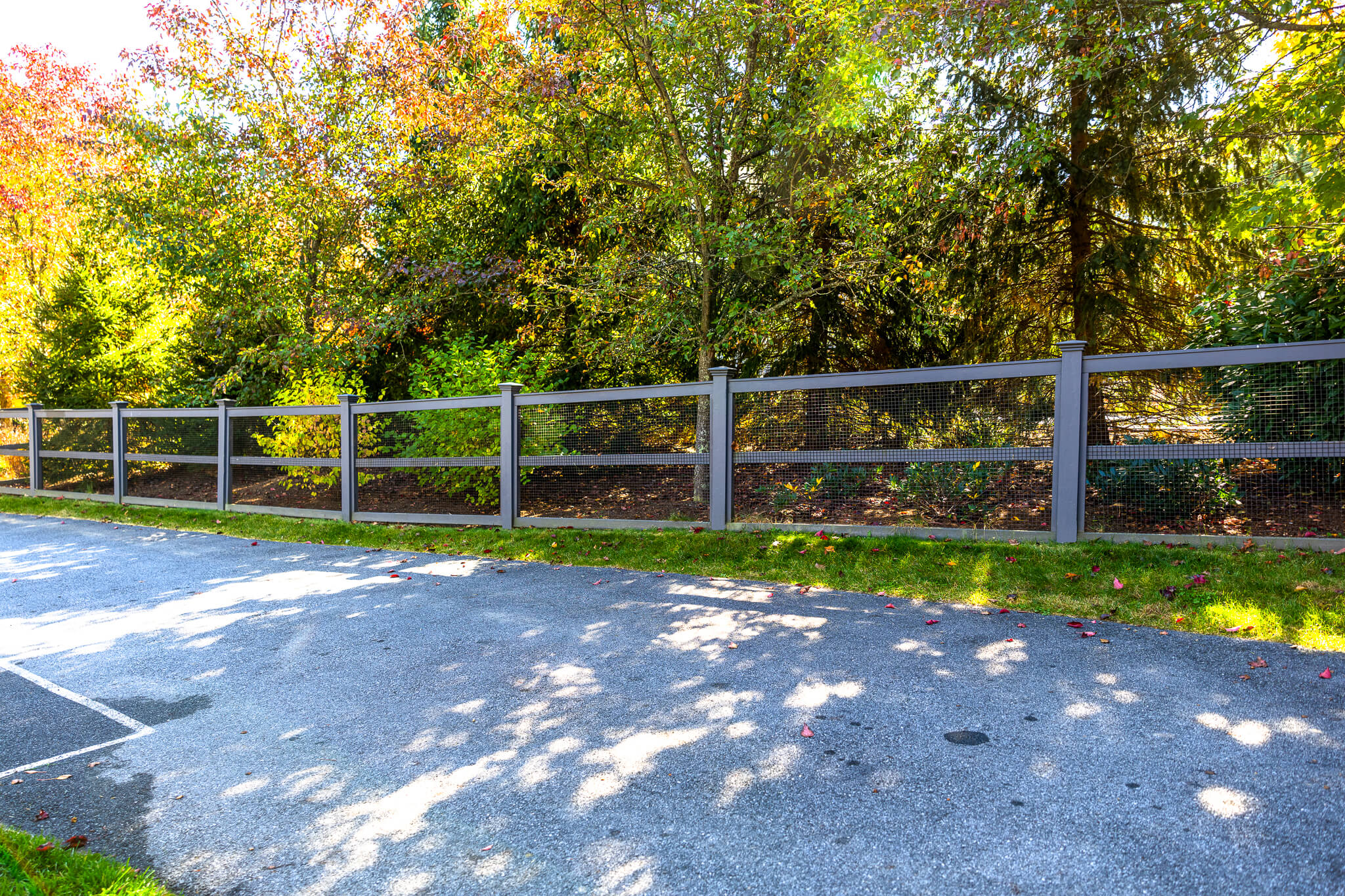 wood horizontal fence with mesh netting for driveway border and ball containment