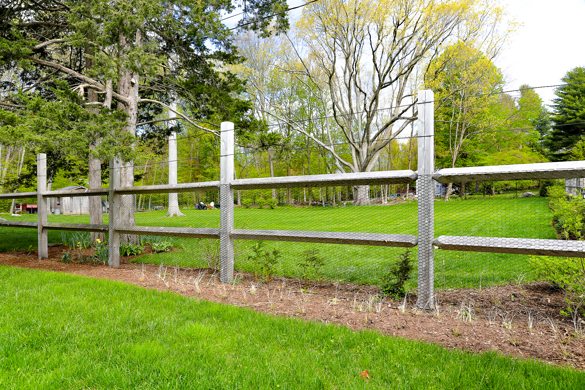 Aged cedar post and rail fence with integrated mesh and wire top for animal containment