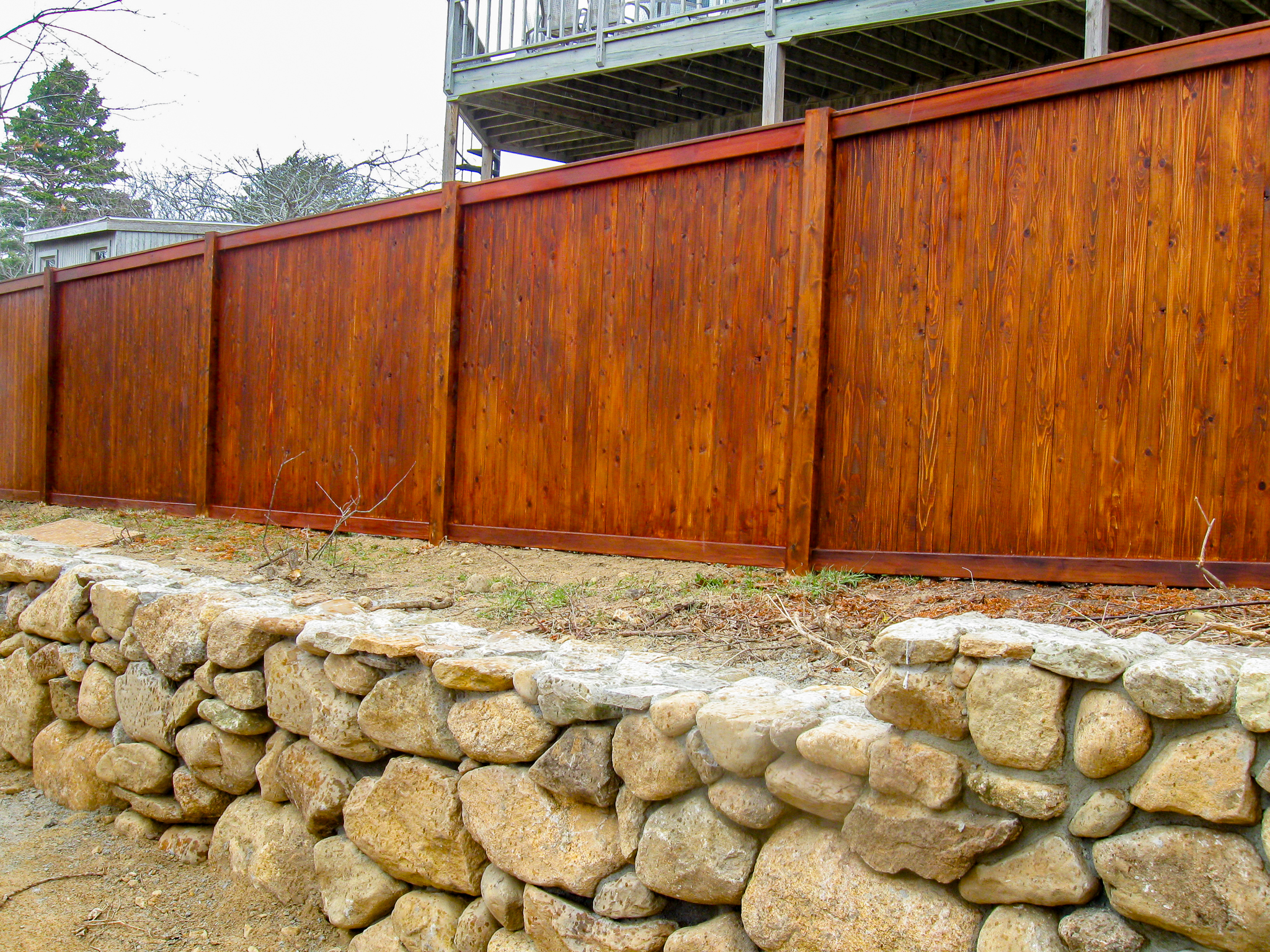 Stained wood fence near a stone retaining wall